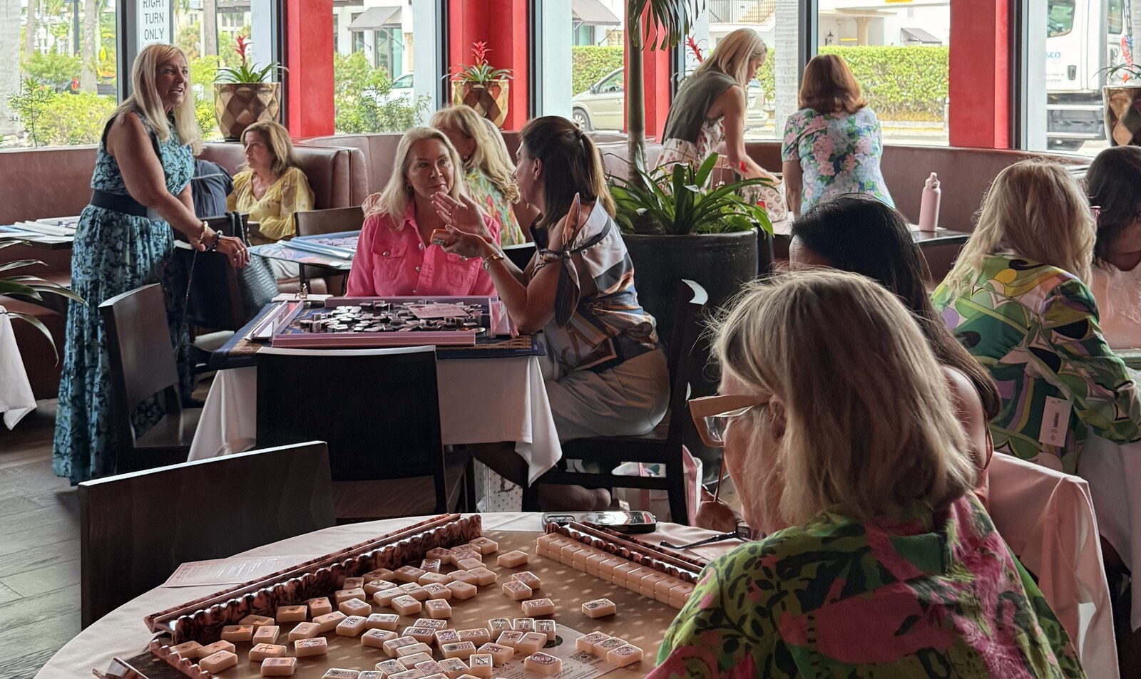 Women playing Mahjong and laughing together at a Hop Toi gathering in Southwest Florida